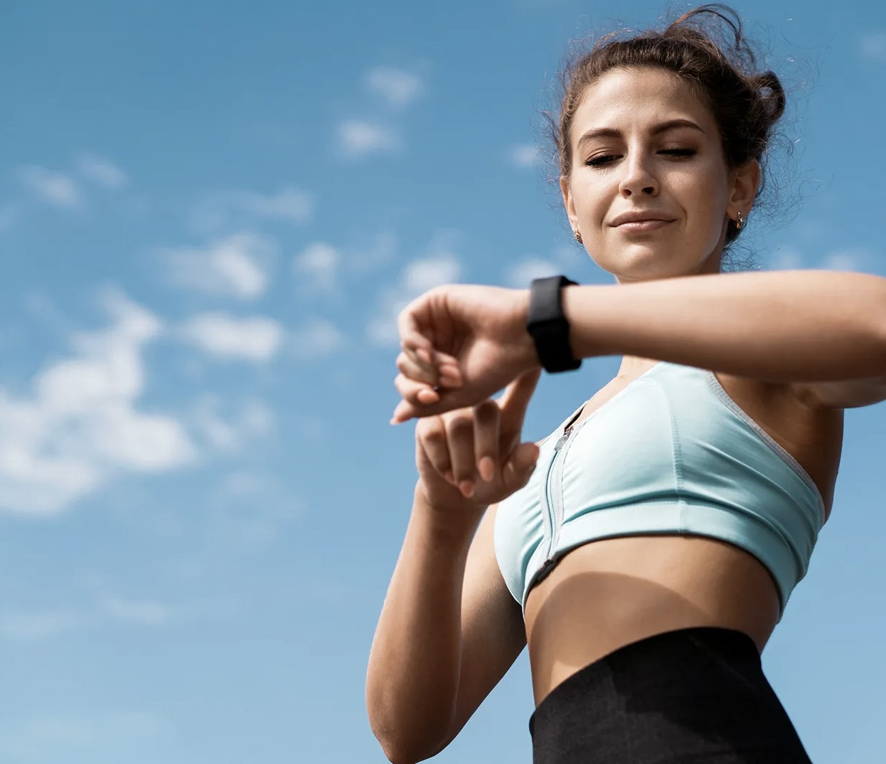 Active woman checking fitness tracker outdoors - representing healthy, active lifestyle after treatment